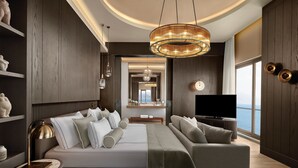 A modern bedroom with a large bed, a sofa, a TV, and a view of the sea. - Akra Antalya (Antalya)