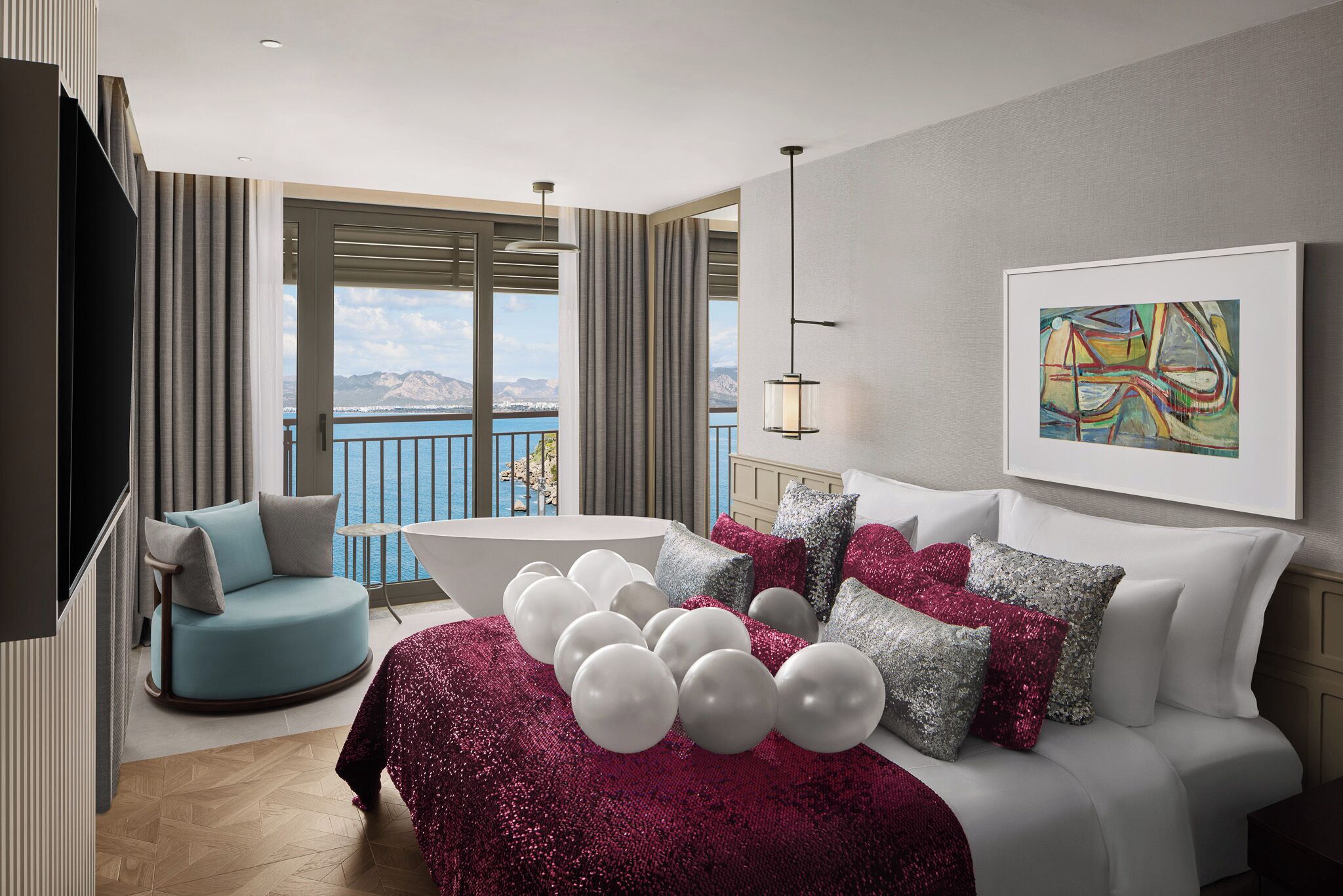 Una camera d'albergo moderna con un letto grande, un'area salotto con una poltrona, vista mare e un quadro appeso al muro.