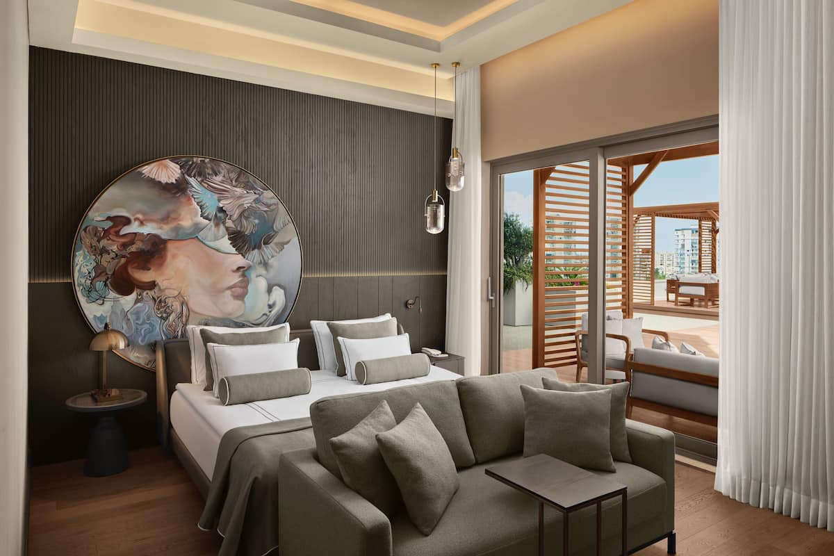 A modern bedroom with a large bed, a sofa, and a large circular artwork on the wall.
