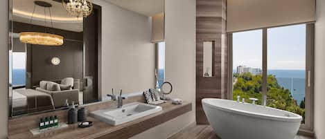 Un baño moderno con una bañera independiente, un espejo grande y vistas al mar.