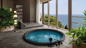 A modern indoor pool area with a view of the sea, a seating area, and a plant arrangement. - Akra Antalya (Antalya)