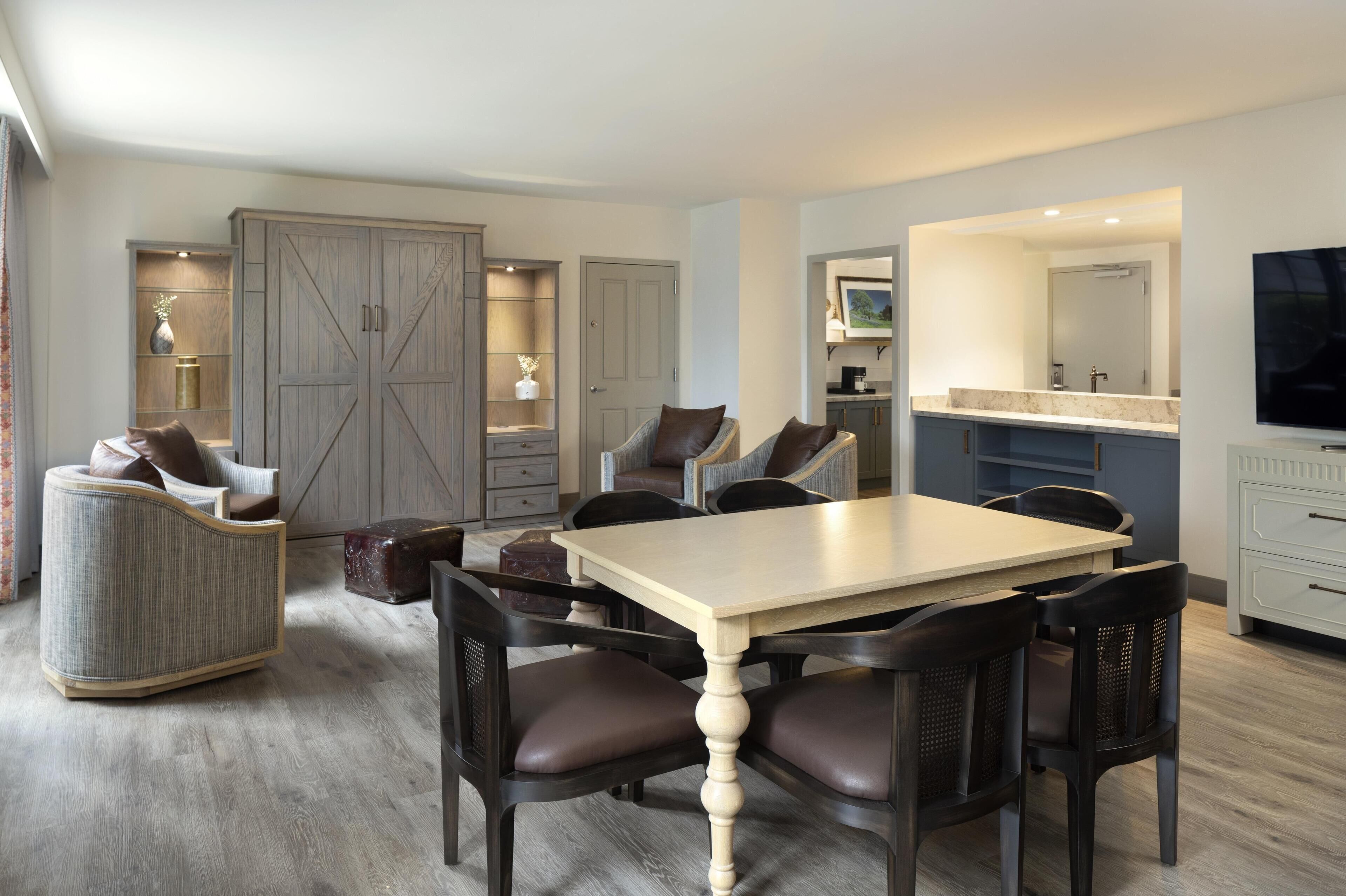 Una sala de estar moderna con una mesa de comedor, sillas, un sofá y un televisor.