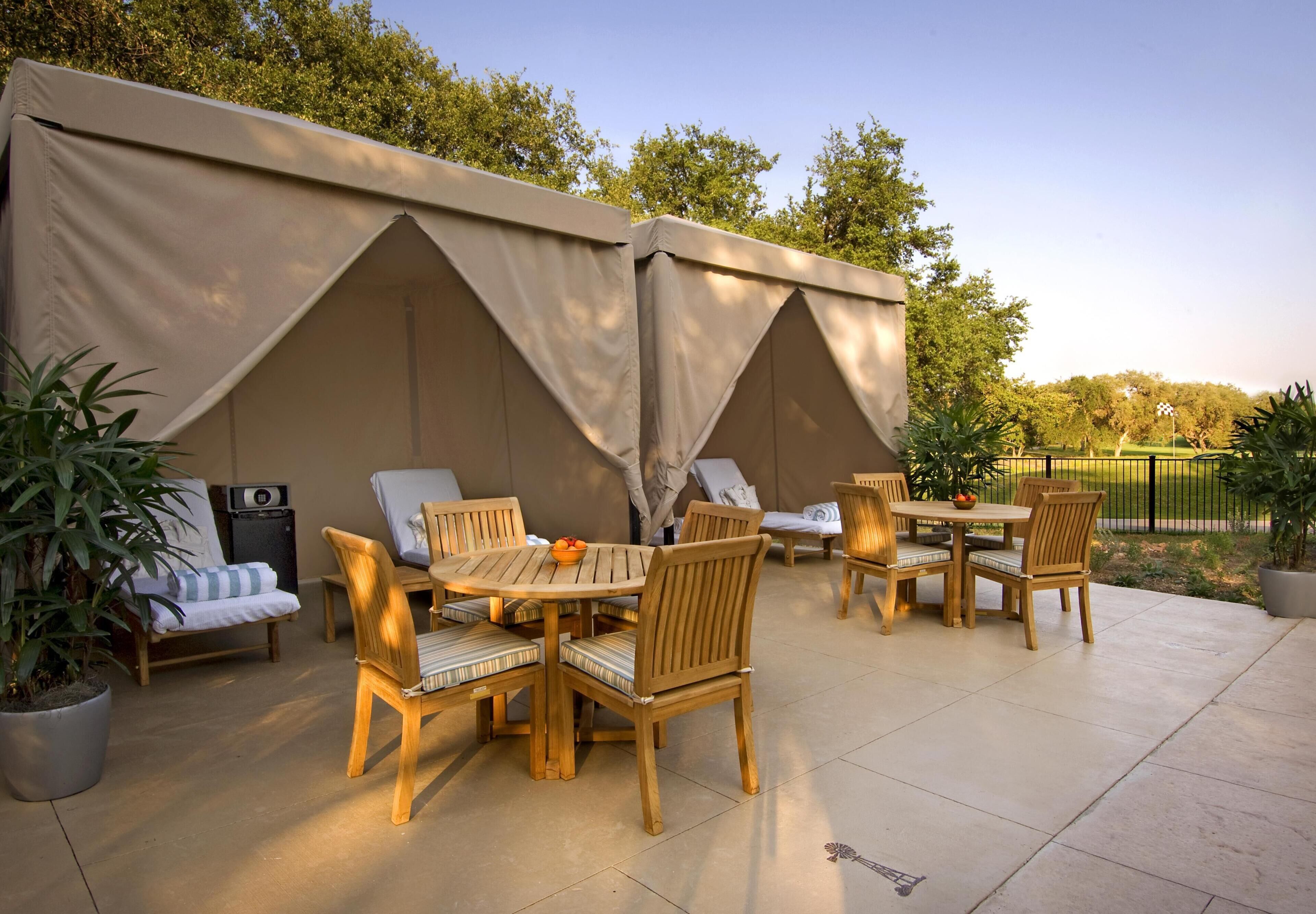 A patio area with wooden furniture, a table, and a tent structure.