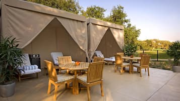A patio area with wooden furniture, a table, and a tent structure.