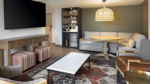 Een moderne woonkamer met een flatscreen-televisie, een bank, een salontafel en een kamerkleed met een patroon.
