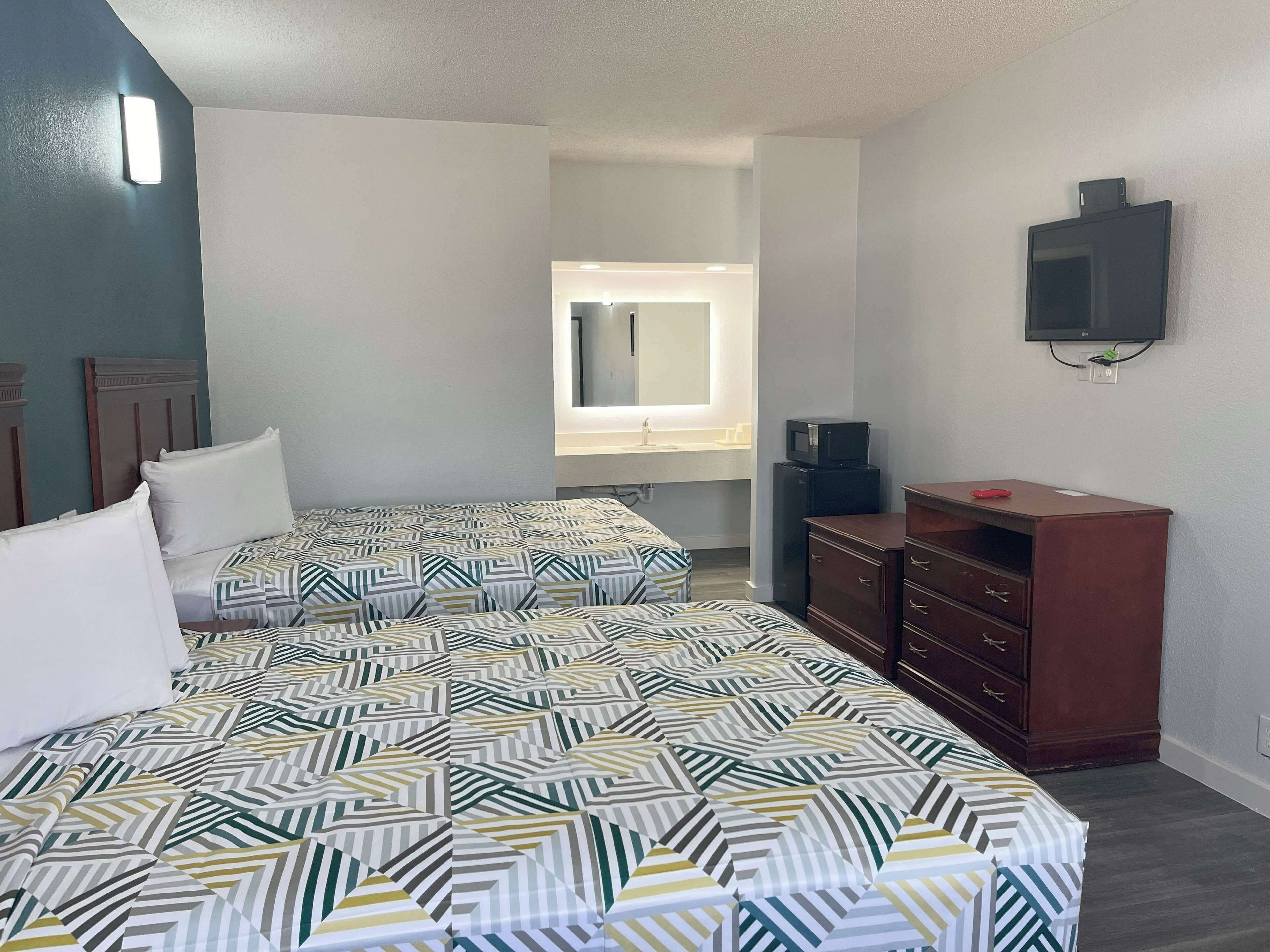 Habitación de hotel con dos camas, un aparador, un televisor y una ventana con vistas.