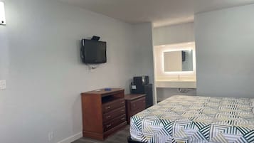 Un dormitorio con cama, cómoda, televisor y espejo con iluminación.