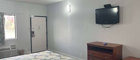 A bedroom with a bed, a dresser, a television, and a door.