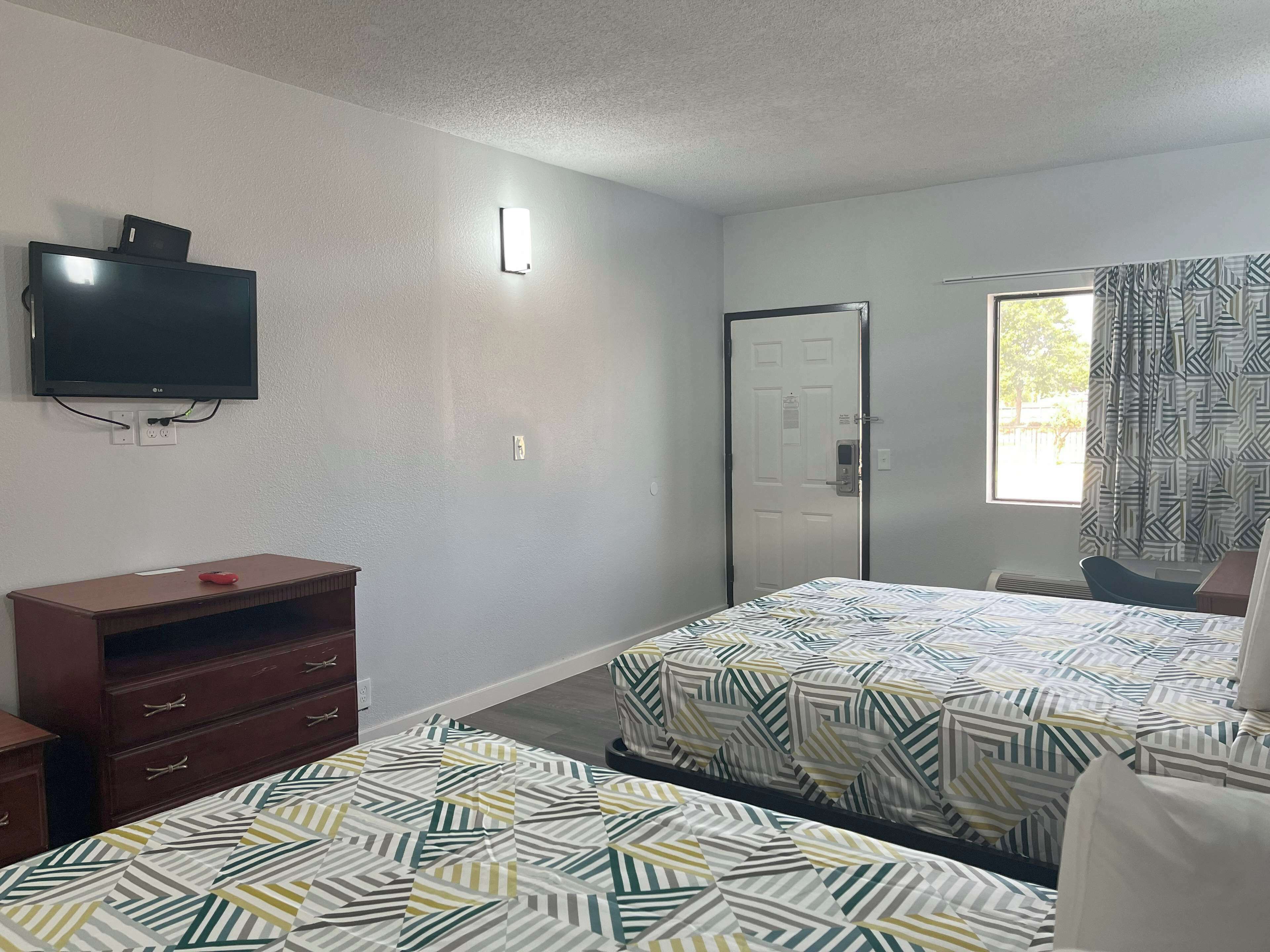 A hotel room with two beds, a TV, a desk, and a wardrobe.