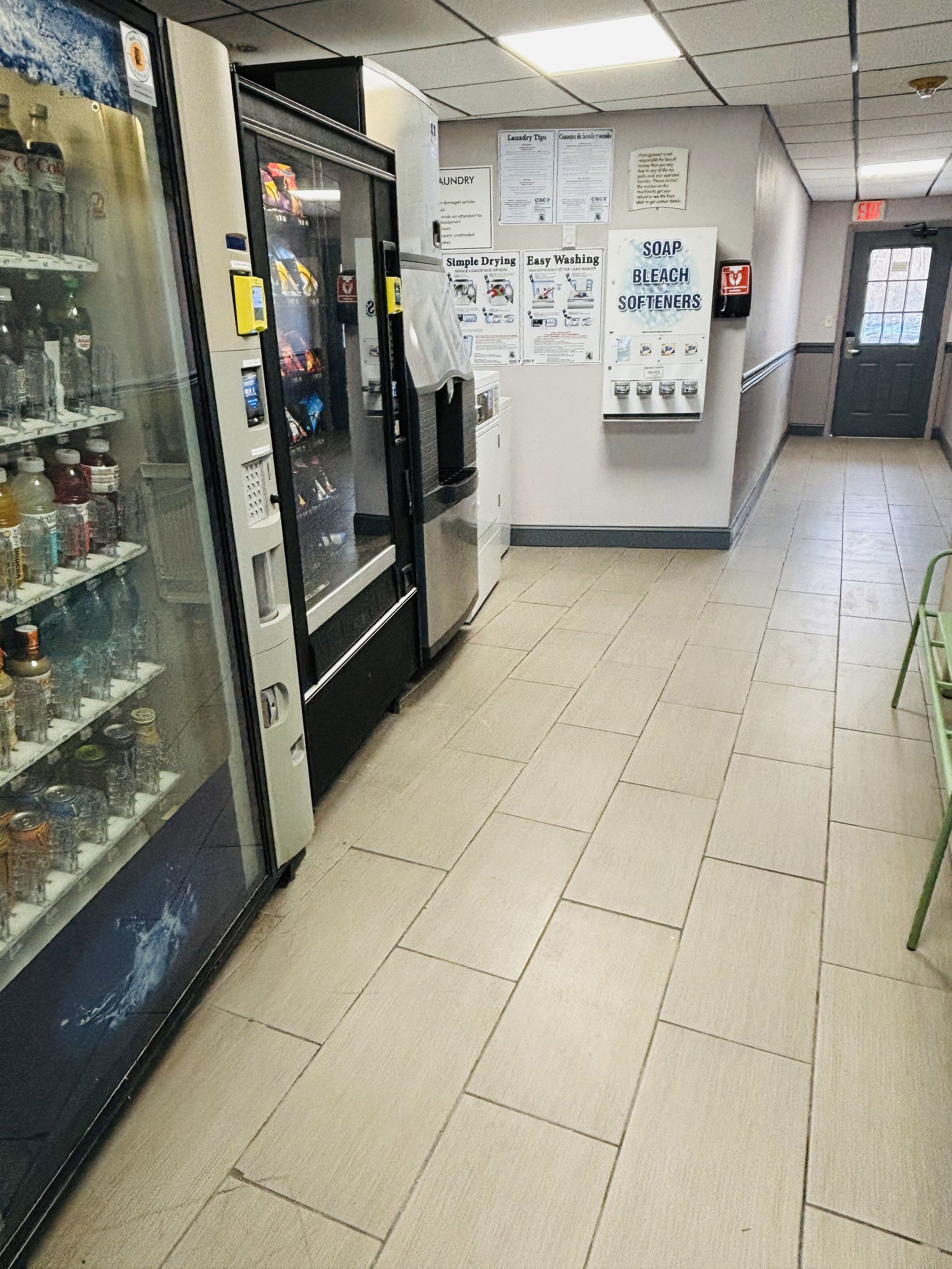 A hallway with a vending machine, a refrigerator, and a wall with laundry tips and soap information.