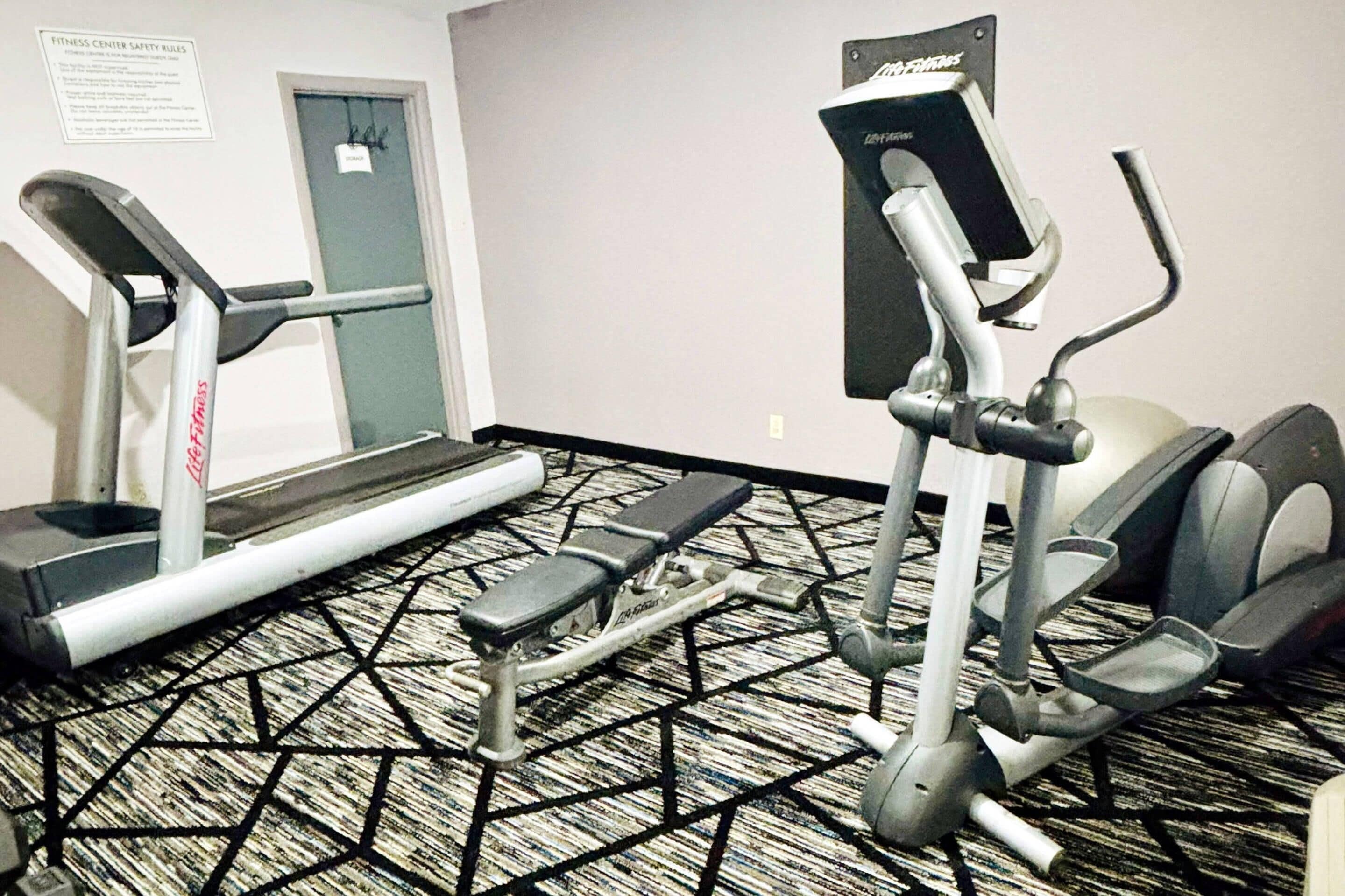 Een fitnessruimte met loopbanden, een elliptische machine en een stepplatform.