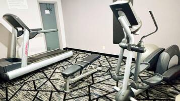 Een fitnessruimte met loopbanden, een elliptische machine en een stepplatform.