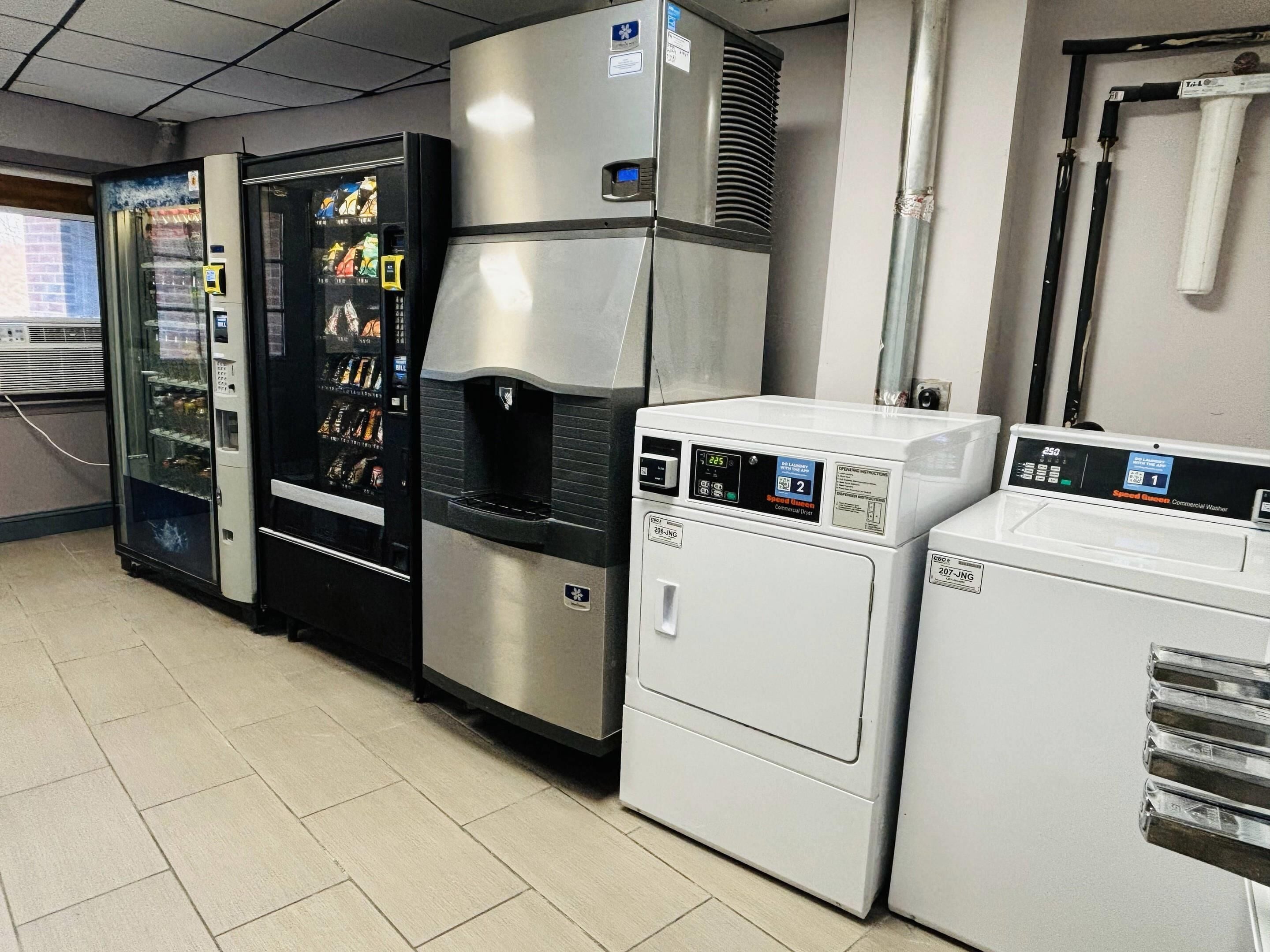 Una cocina comercial con una máquina expendedora, lavadora industrial y un horno grande.