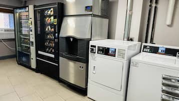 Una cocina comercial con una máquina expendedora, lavadora industrial y un horno grande.