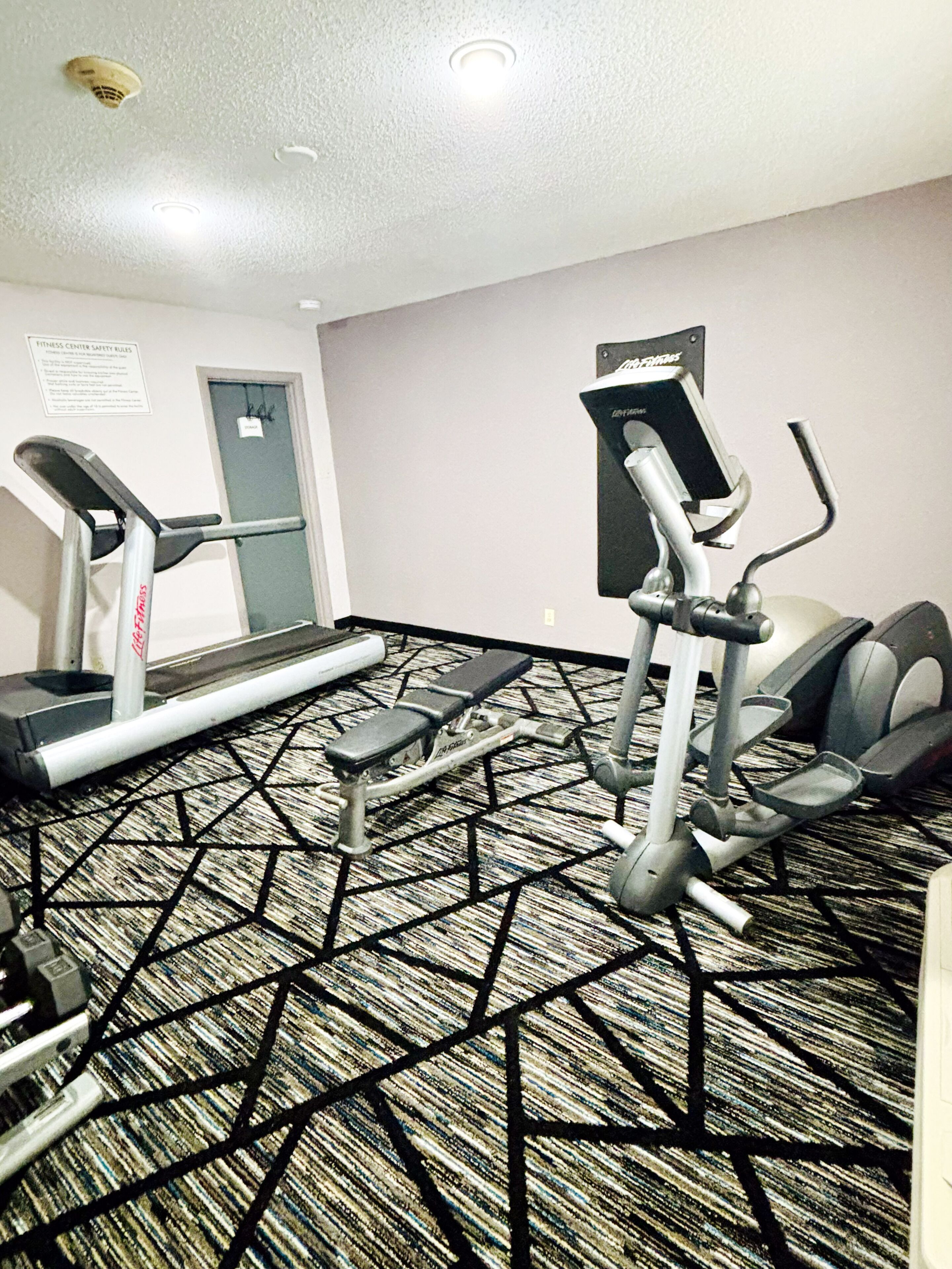 A fitness center with treadmills, an elliptical, and a bench.