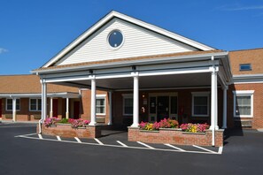 A building with a covered entrance, brick walls, and a circular window above the door.
