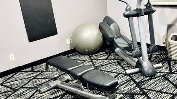 Gimnasio con una plataforma elevada, elíptica y una pelota de ejercicios grande.