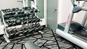 A gym with a treadmill, a bench, and a rack of dumbbells. - Quality Inn Raynham - Taunton (Raynham)