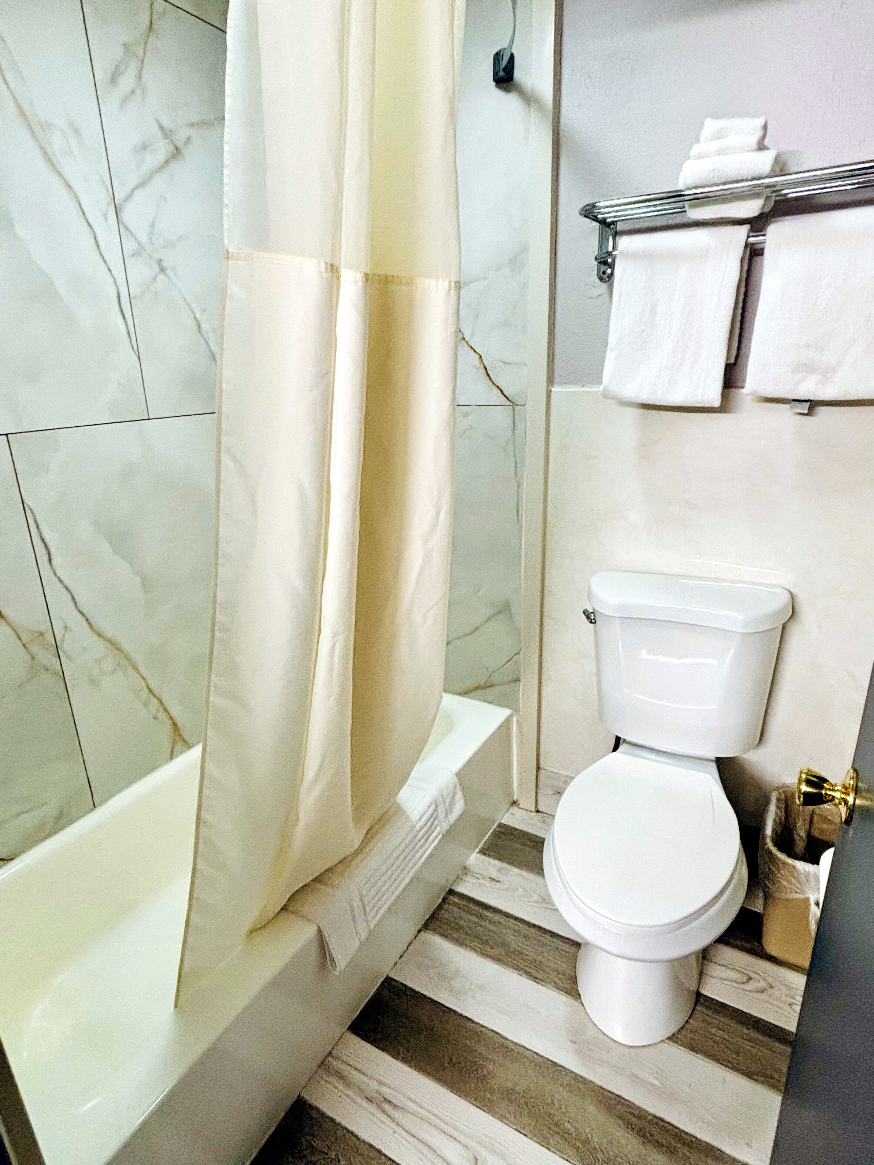 Un baño con bañera, inodoro y cortina de ducha.