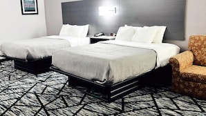 A hotel room with two beds, a nightstand, a chair, and a patterned carpet. - Quality Inn Raynham - Taunton (Raynham)