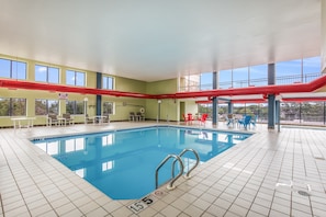Swim and relax in our indoor pool, featuring a clear water surface, metal ladders, and comfortable seating areas.