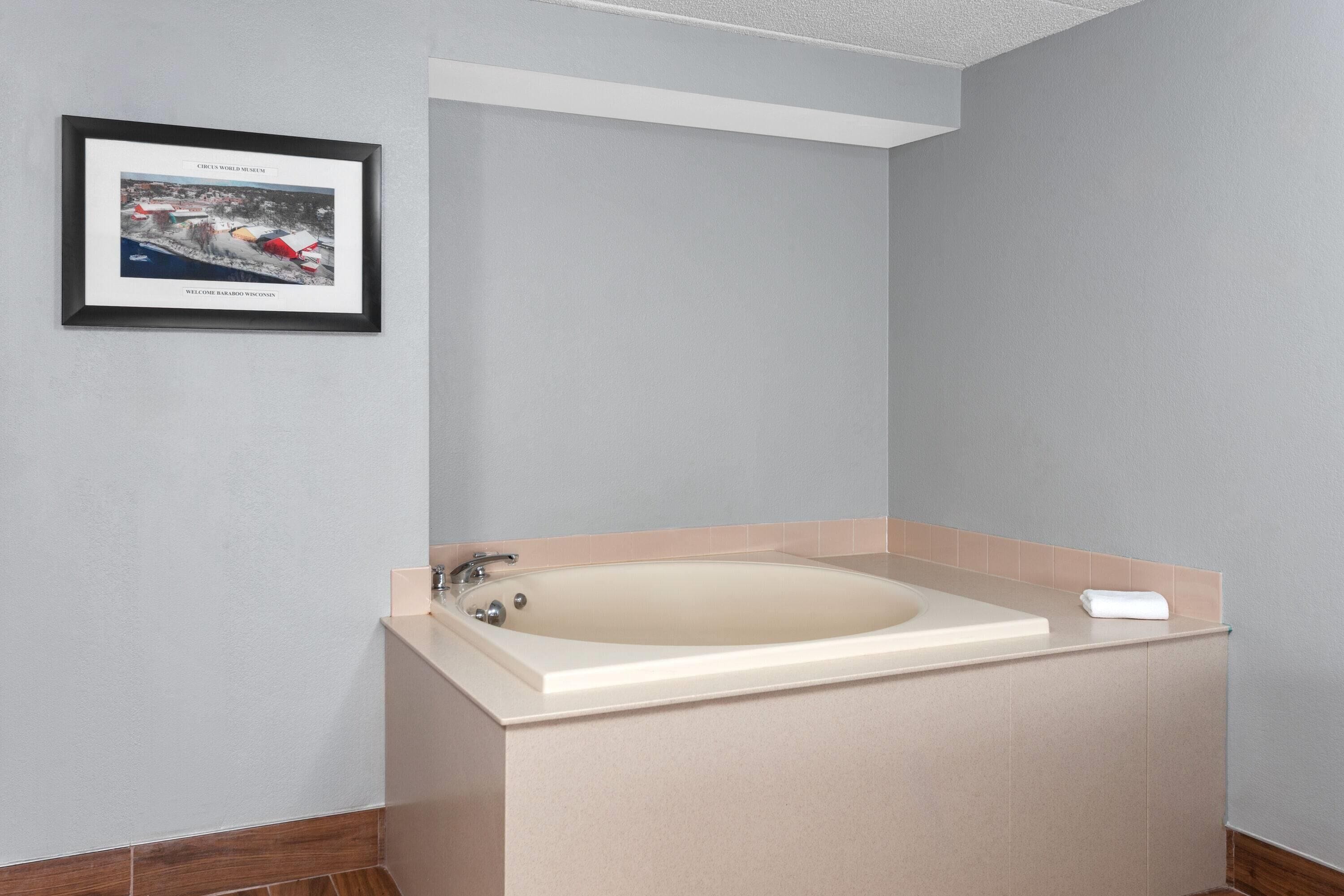Une salle de bain avec une baignoire, un tableau encadré au mur et une serviette posée sur le comptoir.