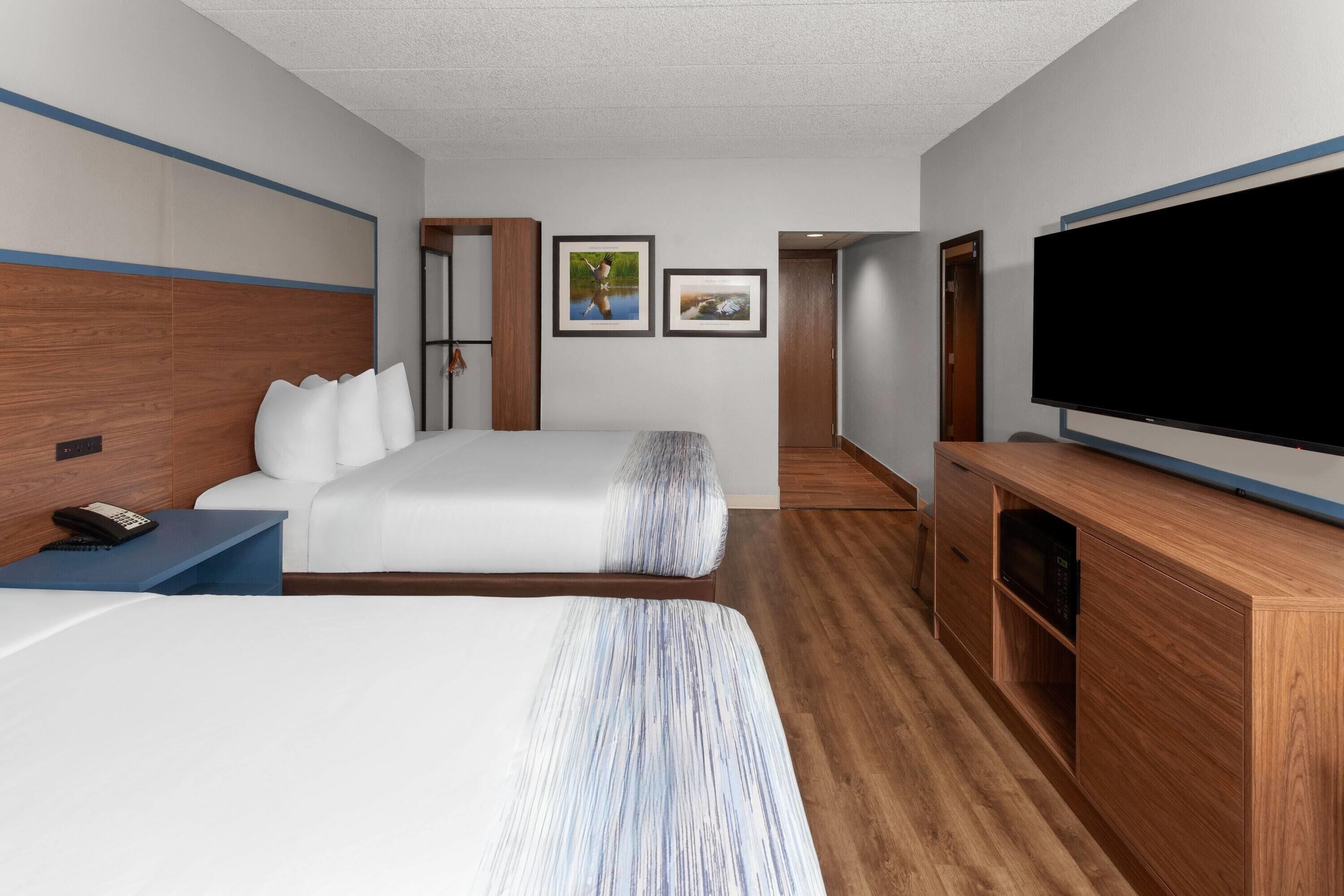 A hotel room with two beds, a TV, a desk, and a wardrobe.