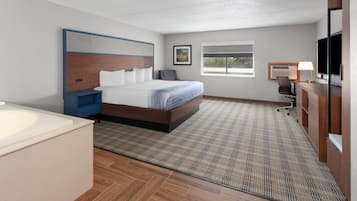 A hotel room with a bed, a desk, a chair, a TV, and a window.