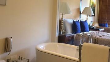 Un bagno con una vasca da bagno freestanding, un water, un mobile vanitario con ripiano in vetro e uno specchio.