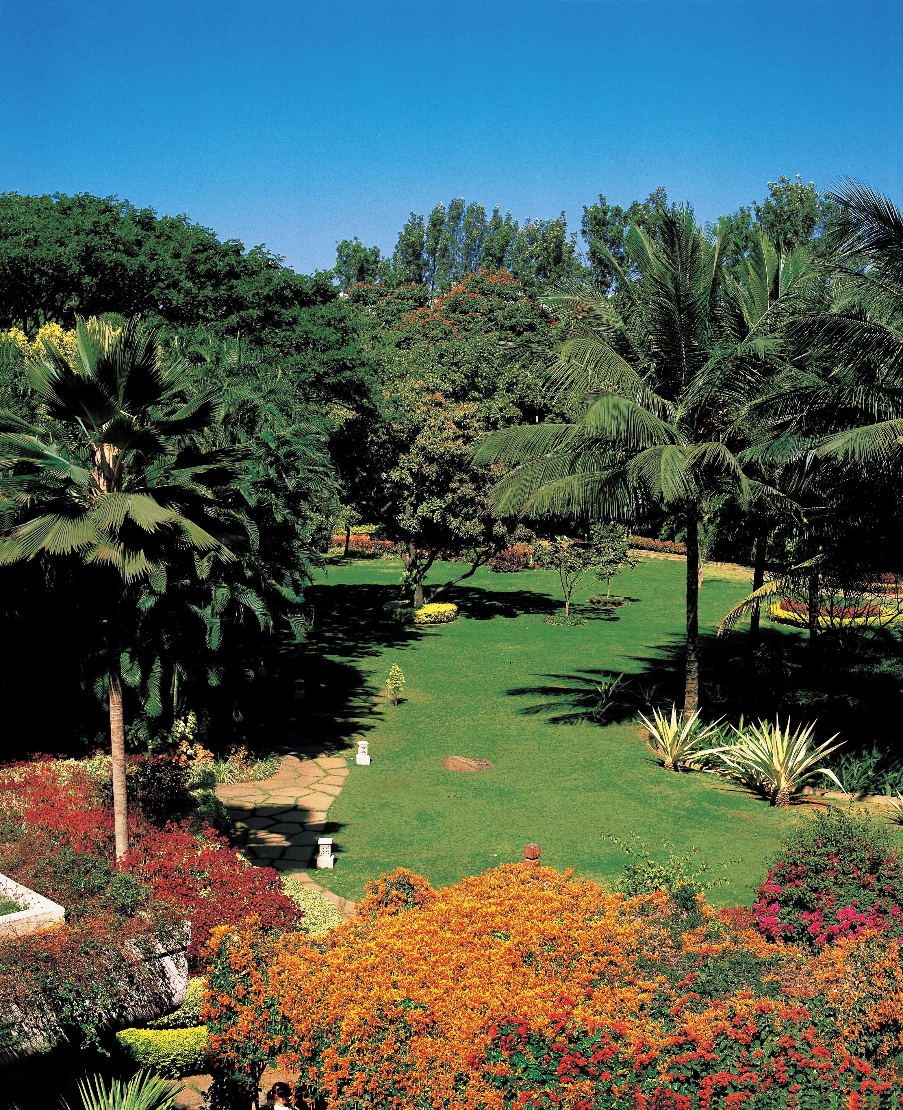 A well-maintained garden with various trees, a lawn, and colorful flower beds.