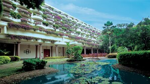 Un hôtel doté d’une grande piscine extérieure, entourée d’une végétation luxuriante et de diverses espèces de plantes.