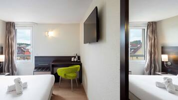 A hotel room with two beds, a desk, a chair, a TV, and a city view.