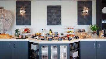 Una barra de desayuno moderna con diversas opciones de alimentos y condimentos, como pan, frutas y bebidas.