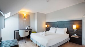 A modern hotel room with a large bed, a desk, and two wall-mounted lamps. - Kyriad Belfort Centre Gare (Belfort)