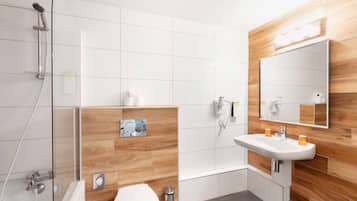 A modern bathroom with a glass-enclosed shower, a white sink, and a wooden accent wall.