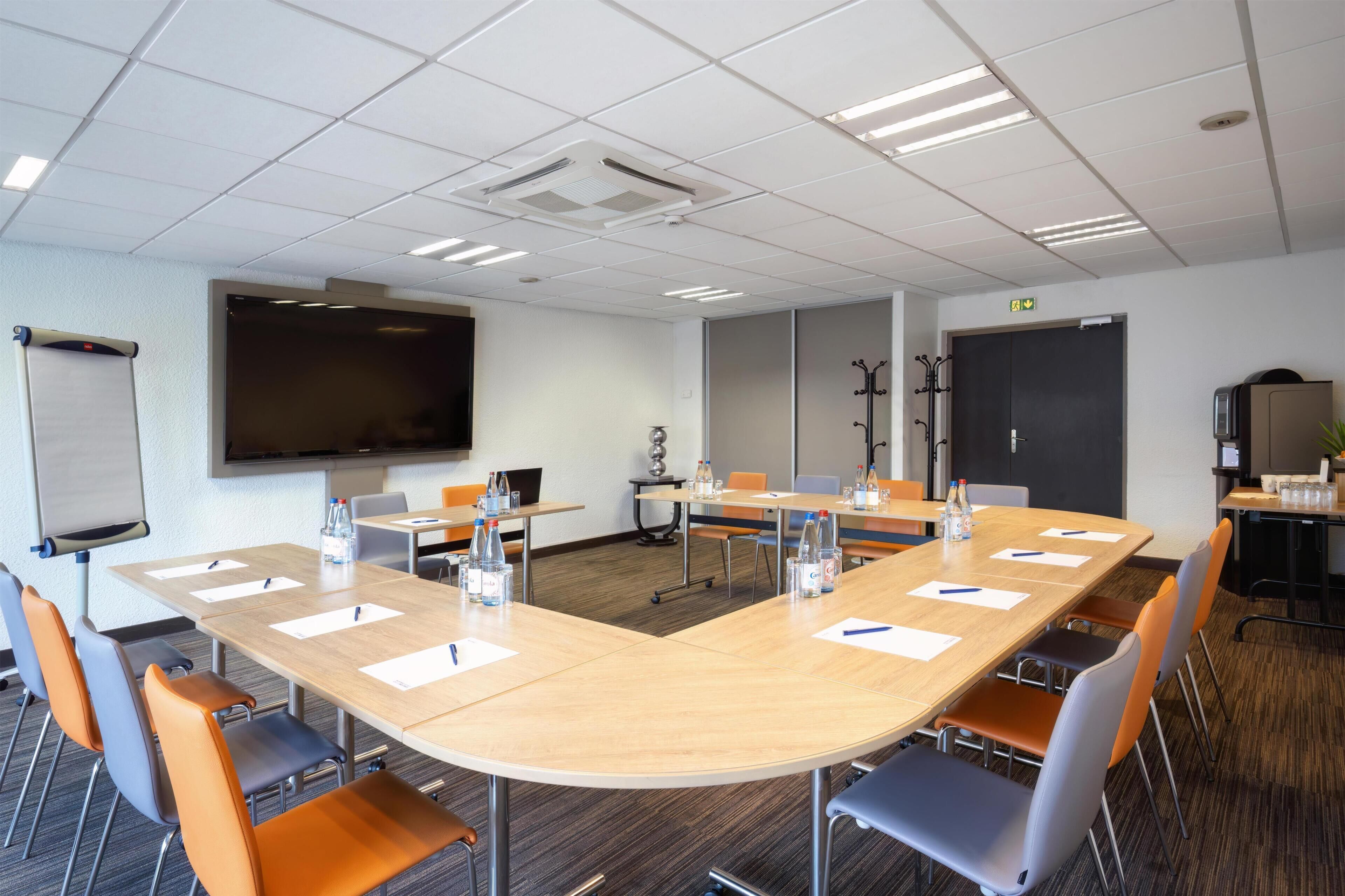 A conference room with a large table, chairs, a whiteboard, and a projection screen.