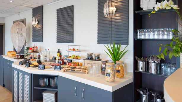 A breakfast buffet with various food items, jars of condiments, and utensils. - Kyriad Belfort Centre Gare (Belfort)