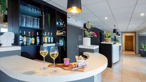 A modern bar area with a curved counter, wine glasses, bottles, and a variety of snacks. - Kyriad Belfort Centre Gare (Belfort)