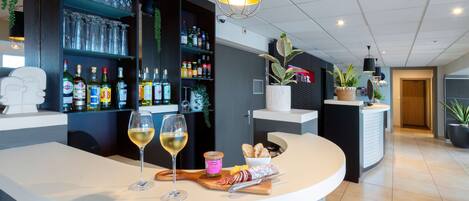 Eine moderne Bar mit einer gebogenen Theke, Weingläsern, Flaschen und verschiedenen Snacks.