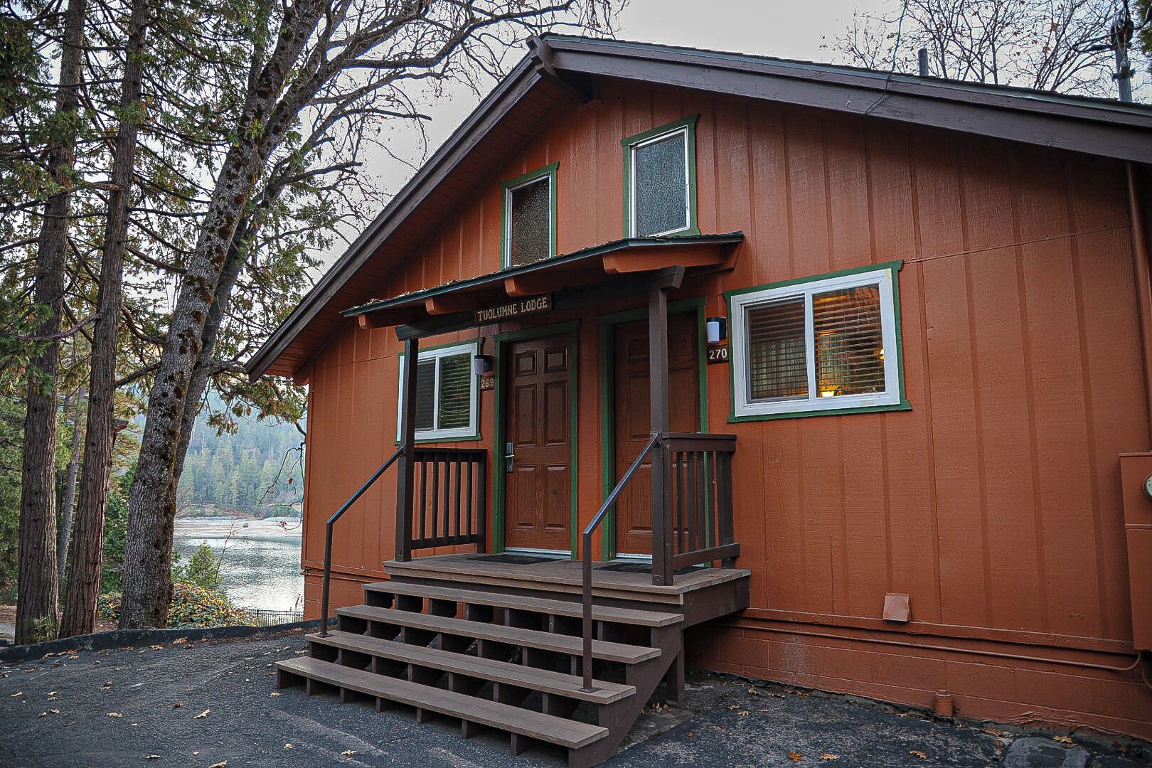 Een houten chalet met een veranda en een trap naar de ingang.