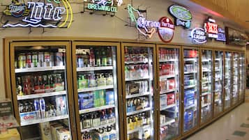 Una hilera de vitrinas refrigeradas para bebidas en una tienda, mostrando diversas marcas de cerveza y refrescos.