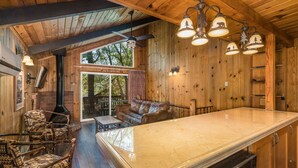 A wooden interior with a large dining table, rustic chairs, and a fireplace. - The Pines Resort (Bass Lake)