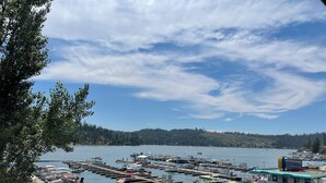 A marina with boats docked, a boat rental service, and a dock with umbrellas and seating. - The Pines Resort (Bass Lake)