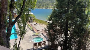 A pool area with a hot tub, lounge chairs, and a deck overlooking a lake. - The Pines Resort (Bass Lake)