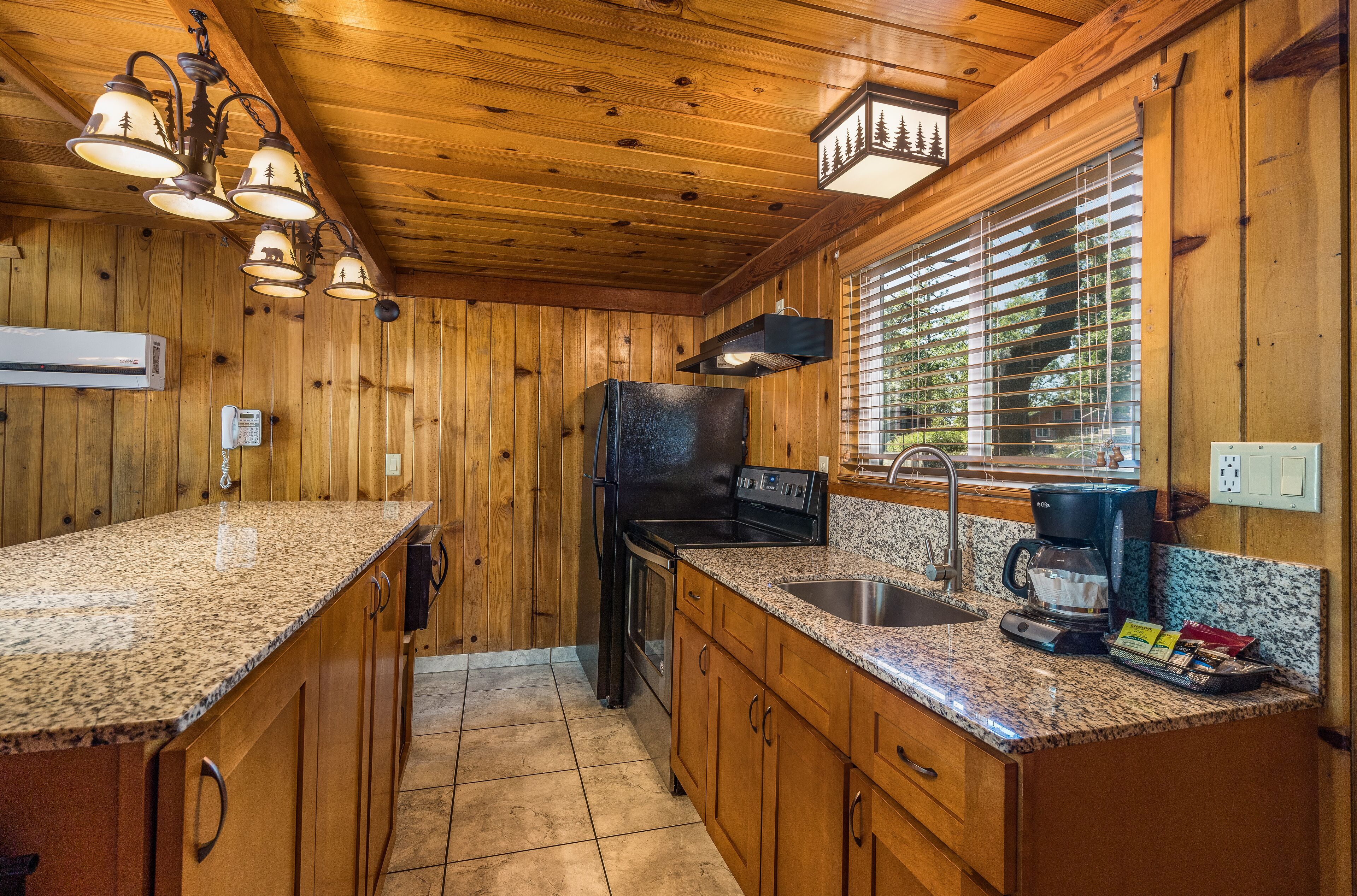 Cocina de cabaña de madera con encimeras de granito, refrigerador, estufa y cafetera.