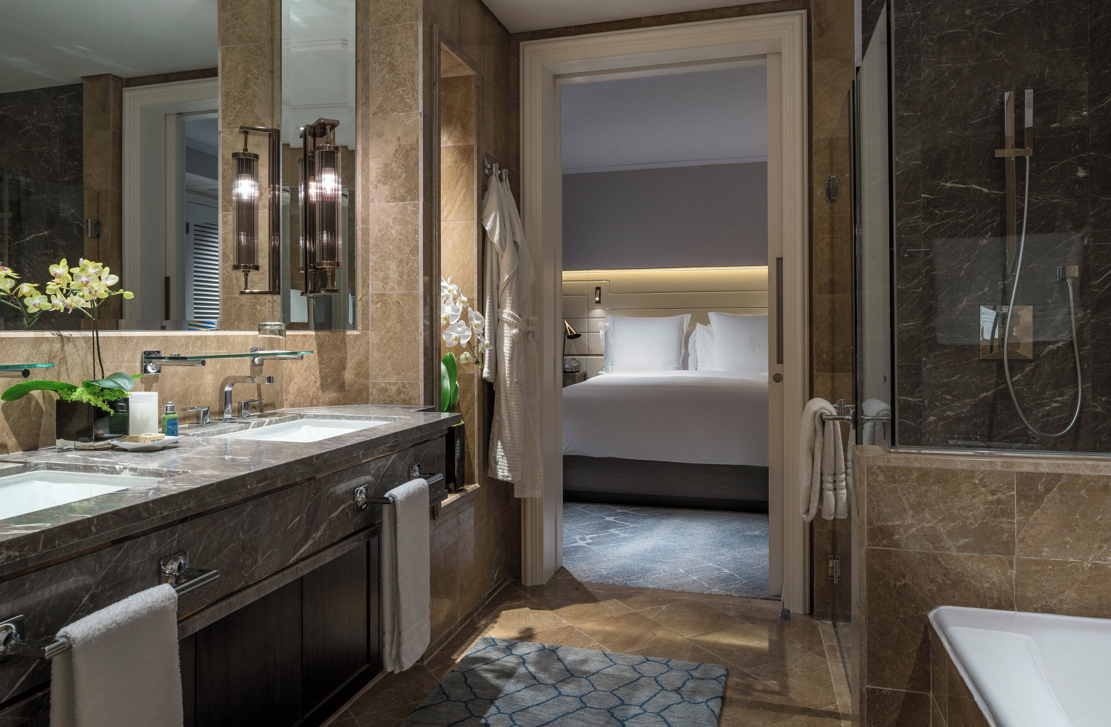 Un baño moderno con lavamanos dobles, un espejo grande y una ducha a ras de suelo.