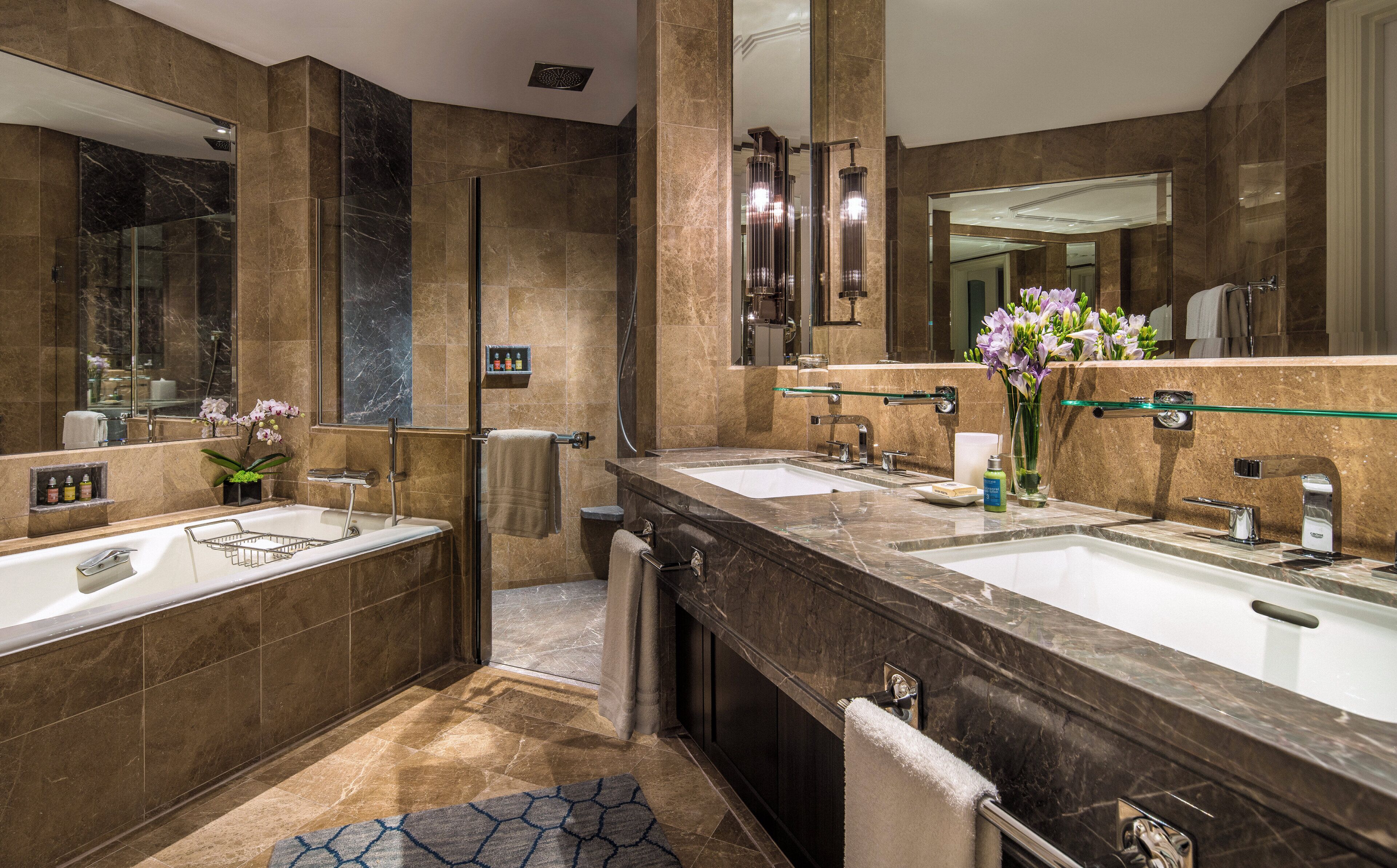 A modern bathroom with two sinks, a glass shower enclosure, and a large mirror.