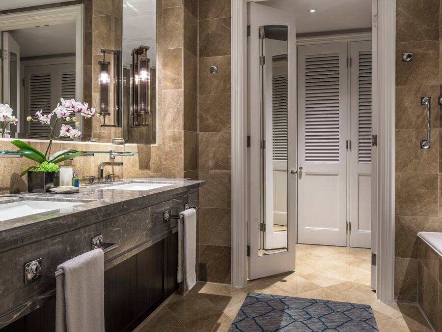 Un bagno moderno con due lavabi, un grande specchio e un'orchidea in vaso.