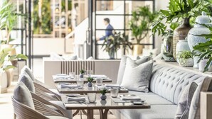 A modern dining area with a long table, cushioned seating, and potted plants. - Four Seasons Hotel Singapore (Singapore)