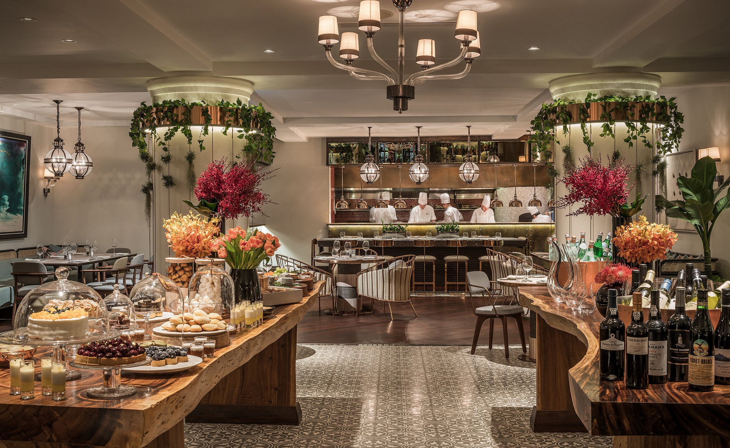 Ein Restaurant mit Barbereich, Kochstation und einem Buffet mit verschiedenen Desserts und Getränken.